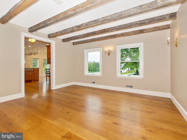 unfurnished room with beamed ceiling, light hardwood / wood-style floors, and a notable chandelier