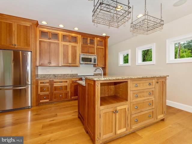 kitchen with light stone countertops, a healthy amount of sunlight, light wood-type flooring, and appliances with stainless steel finishes