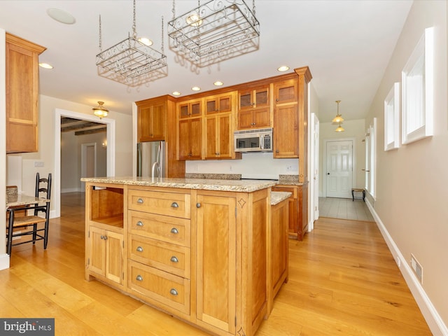 kitchen featuring decorative light fixtures, light hardwood / wood-style flooring, stainless steel appliances, light stone countertops, and a center island