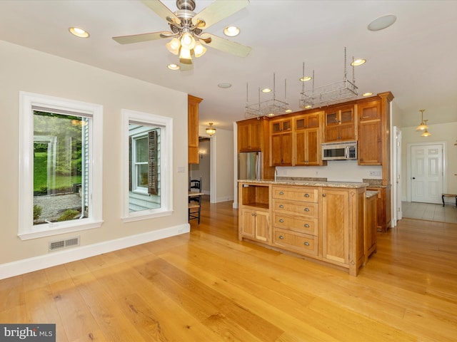 kitchen with stainless steel appliances, ceiling fan, light tile flooring, and light stone counters