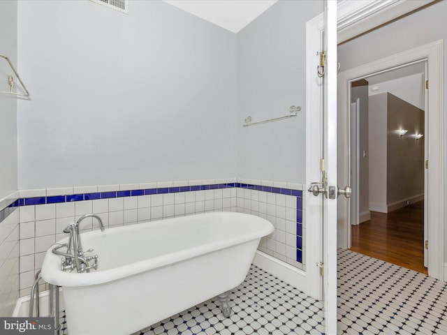 bathroom featuring a washtub, tile walls, and tile floors