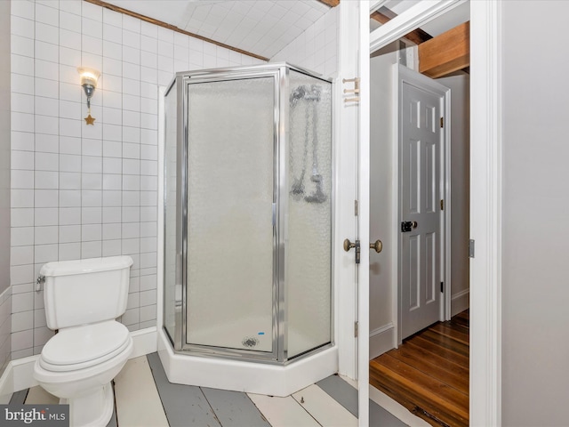 bathroom featuring tile walls, tile floors, a shower with door, and toilet