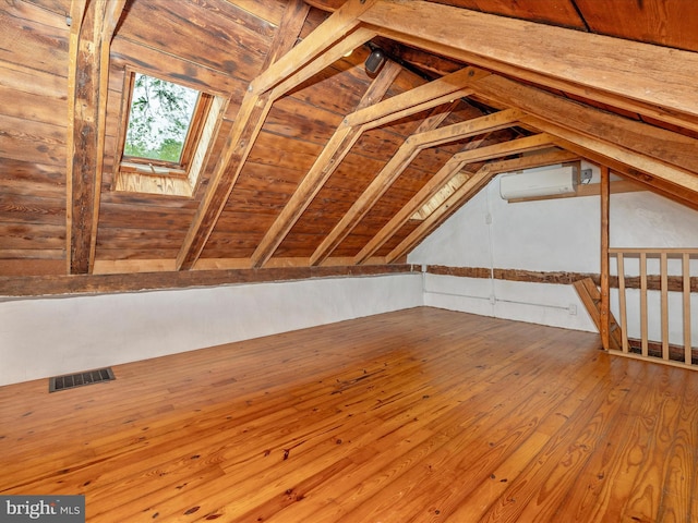 attic with a wall mounted AC and a skylight