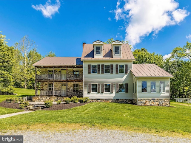 view of front of house featuring a front lawn and a balcony