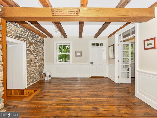 unfurnished living room featuring beam ceiling and dark hardwood / wood-style floors