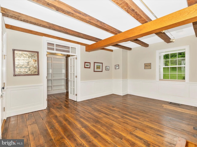 spare room featuring beam ceiling and dark hardwood / wood-style floors