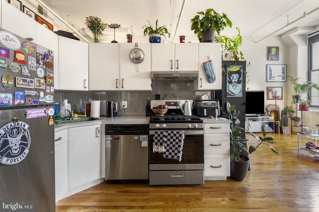 kitchen featuring hardwood / wood-style floors, appliances with stainless steel finishes, beam ceiling, sink, and tasteful backsplash