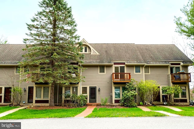 view of property featuring a front lawn and a balcony