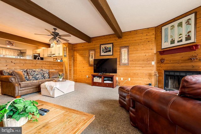 living room with wooden walls, beam ceiling, ceiling fan, and carpet floors