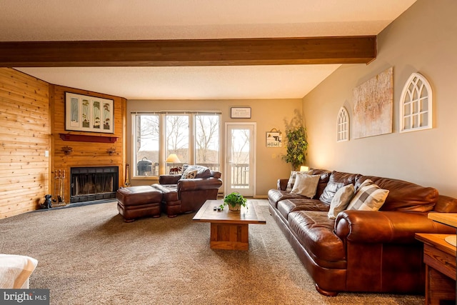 living room featuring beamed ceiling, a textured ceiling, a large fireplace, wooden walls, and carpet floors