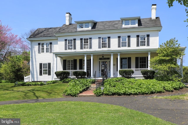 colonial home with a front lawn and covered porch