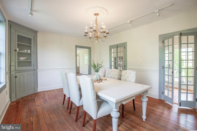dining area with french doors, a chandelier, rail lighting, and dark hardwood / wood-style floors