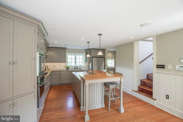 kitchen featuring pendant lighting, stainless steel appliances, a center island, and light wood-type flooring