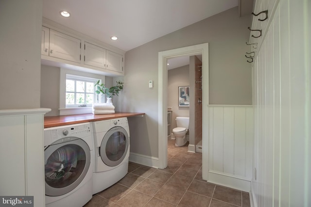 laundry room featuring washing machine and dryer, cabinets, and tile flooring