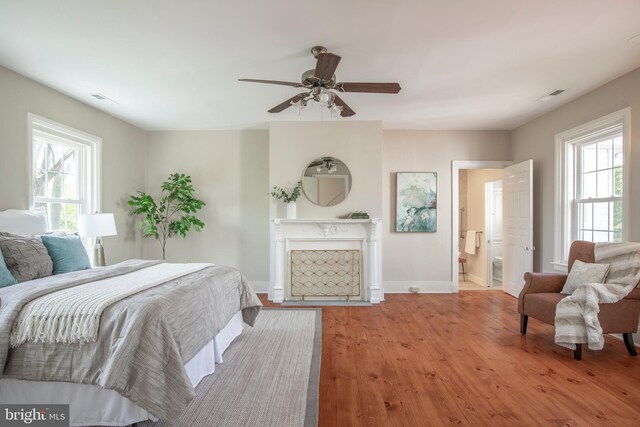 bedroom featuring ceiling fan, hardwood / wood-style flooring, and connected bathroom