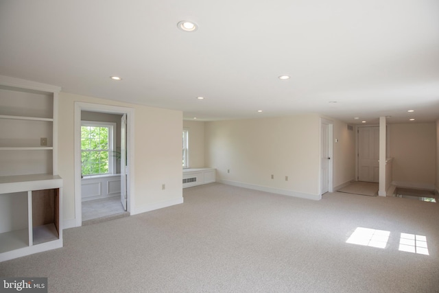 unfurnished room featuring light carpet and built in shelves