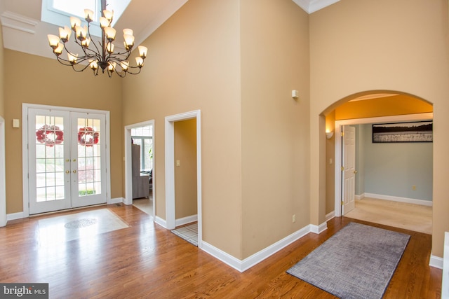 entrance foyer featuring an inviting chandelier, hardwood / wood-style flooring, french doors, and a high ceiling