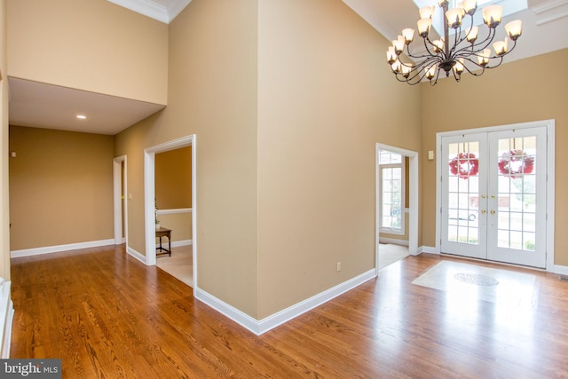 foyer entrance with an inviting chandelier, wood-type flooring, french doors, and a towering ceiling