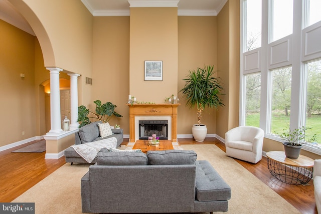 living room featuring crown molding, hardwood / wood-style floors, and decorative columns