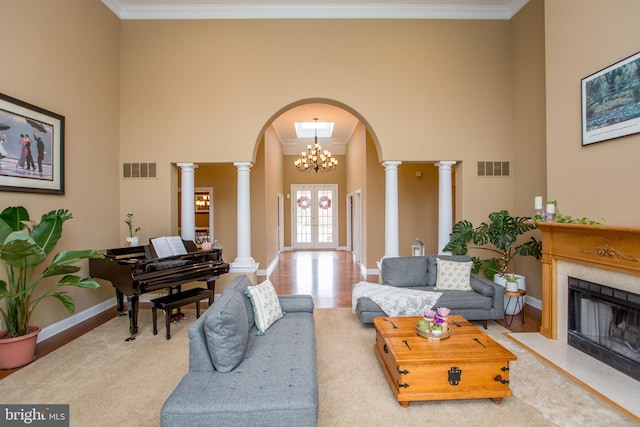 living room featuring an inviting chandelier, ornamental molding, ornate columns, and light hardwood / wood-style floors