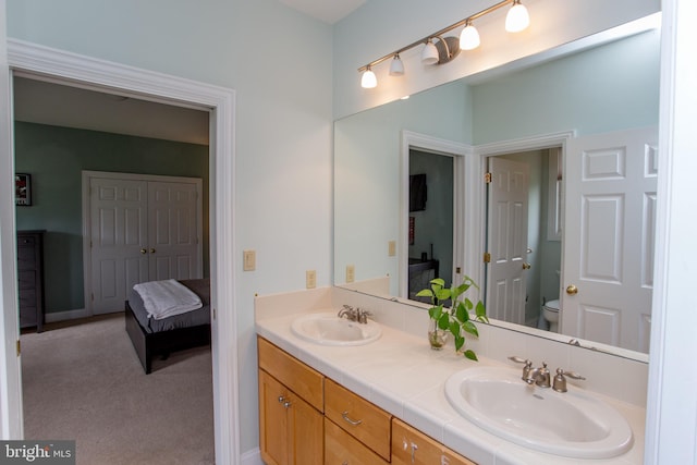 bathroom with toilet and dual bowl vanity