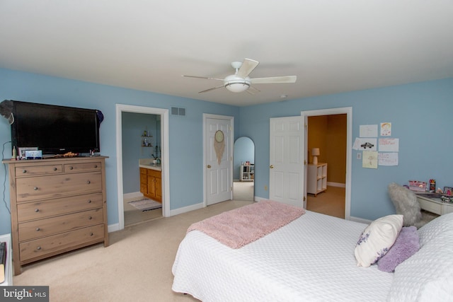 bedroom featuring ensuite bath, light colored carpet, and ceiling fan