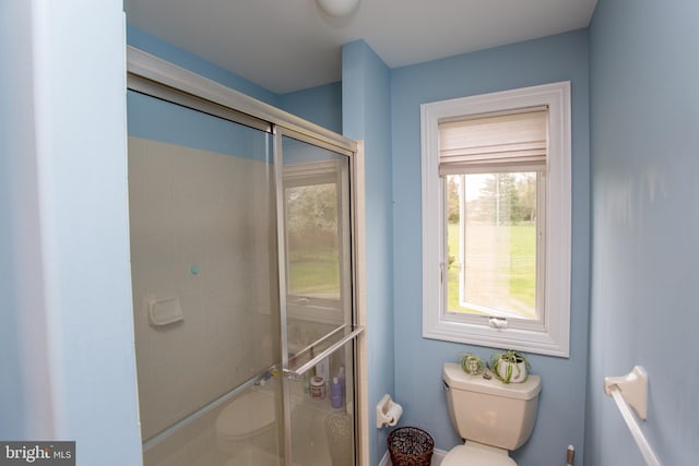 bathroom featuring a shower with shower door and toilet