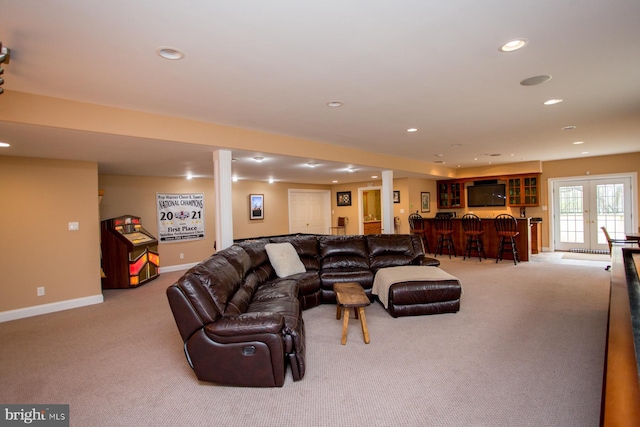 carpeted living room with ornate columns, indoor bar, and french doors