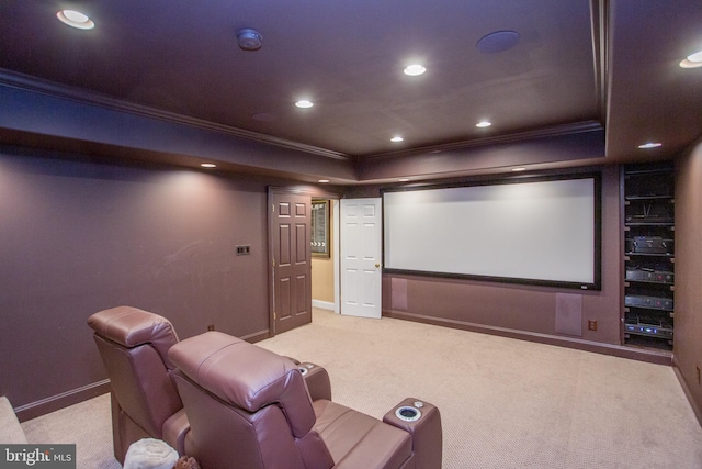 carpeted home theater room with ornamental molding and a raised ceiling