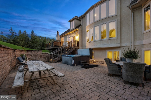 patio terrace at dusk with a hot tub and an outdoor hangout area