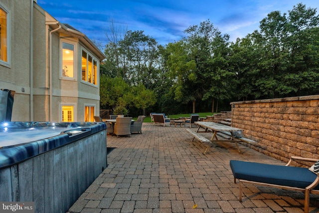 patio terrace at dusk featuring a hot tub