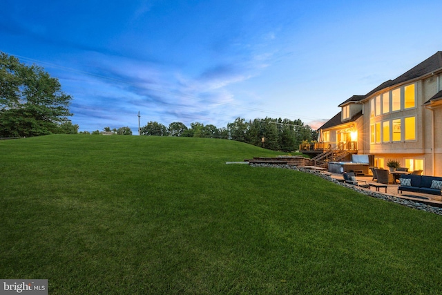 yard at dusk with an outdoor living space and a patio