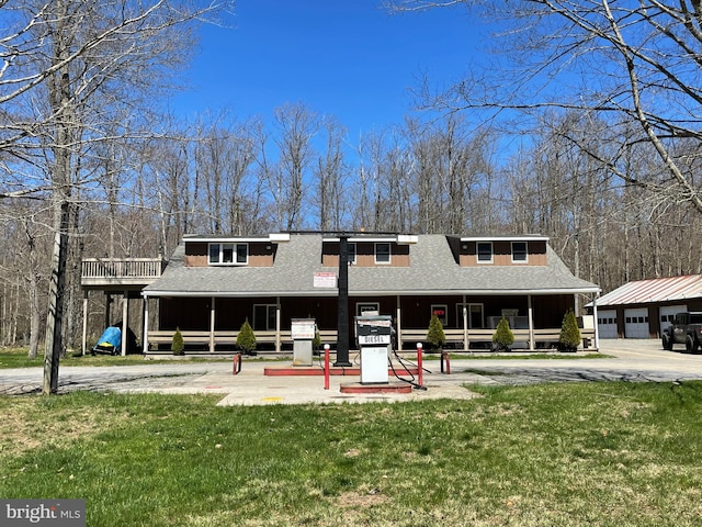 back of house with a garage, a lawn, and an outdoor structure