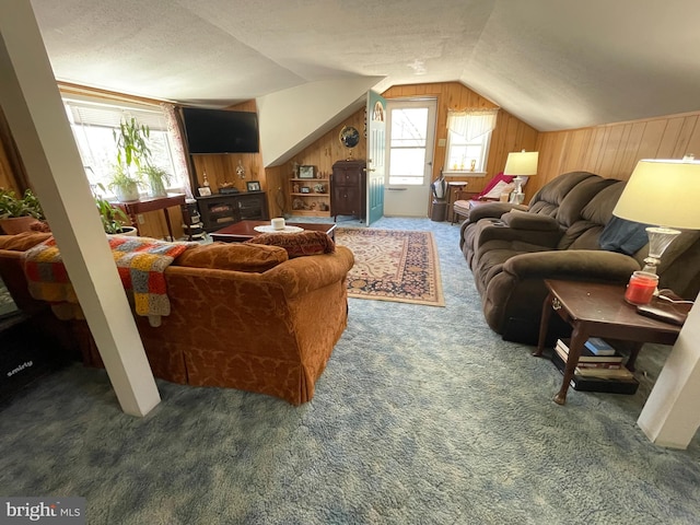 carpeted living room featuring lofted ceiling, a textured ceiling, plenty of natural light, and wooden walls