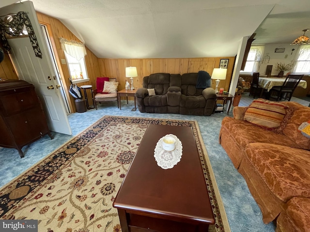 living room with vaulted ceiling, wood walls, and carpet flooring