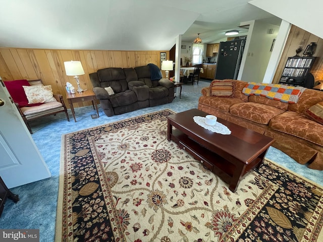 carpeted living room with lofted ceiling and wooden walls