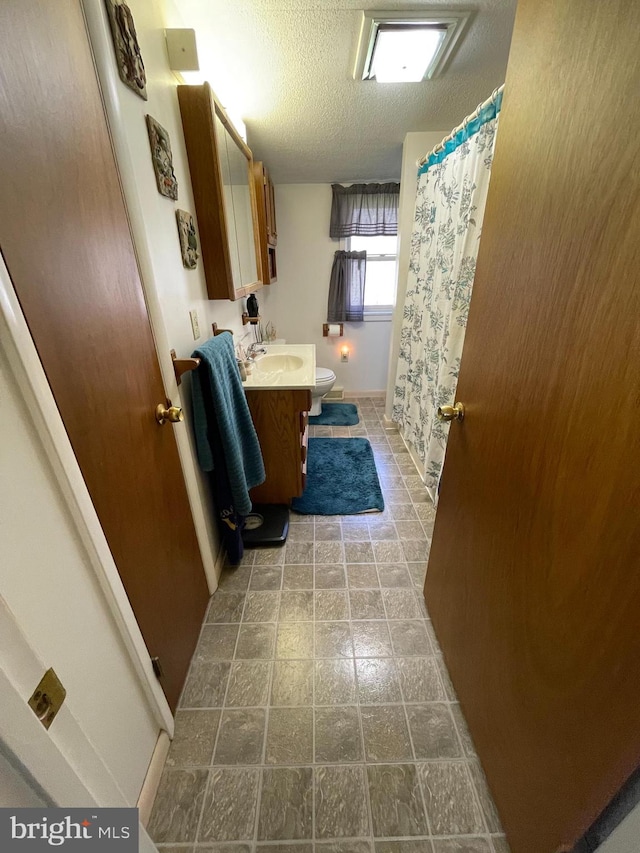 bathroom with a textured ceiling, oversized vanity, tile floors, and toilet