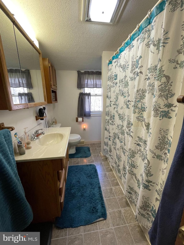 bathroom with vanity, toilet, tile floors, and a textured ceiling