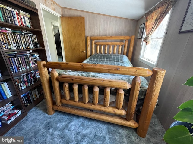 carpeted bedroom with crown molding and wooden walls