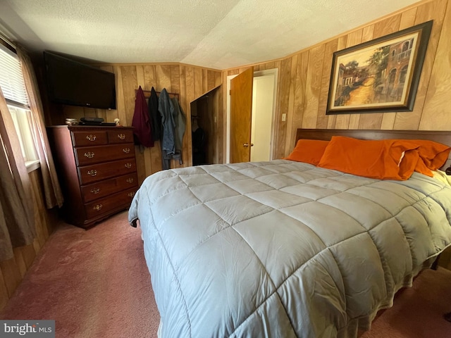 bedroom with lofted ceiling, wood walls, a textured ceiling, and carpet flooring