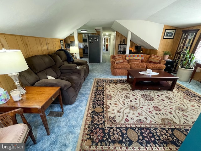 living room featuring lofted ceiling, wood walls, and carpet flooring