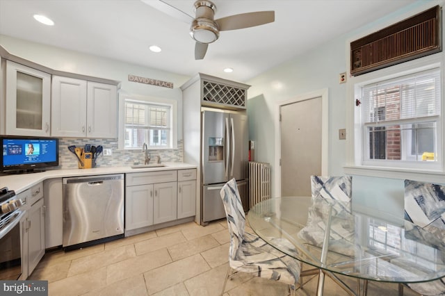 kitchen with backsplash, stainless steel appliances, sink, light tile floors, and ceiling fan