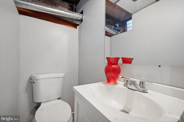 bathroom with toilet, oversized vanity, and a textured ceiling