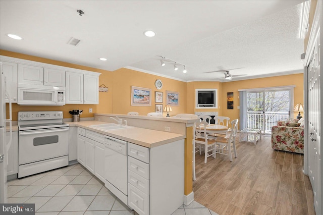 kitchen with sink, white appliances, kitchen peninsula, and track lighting