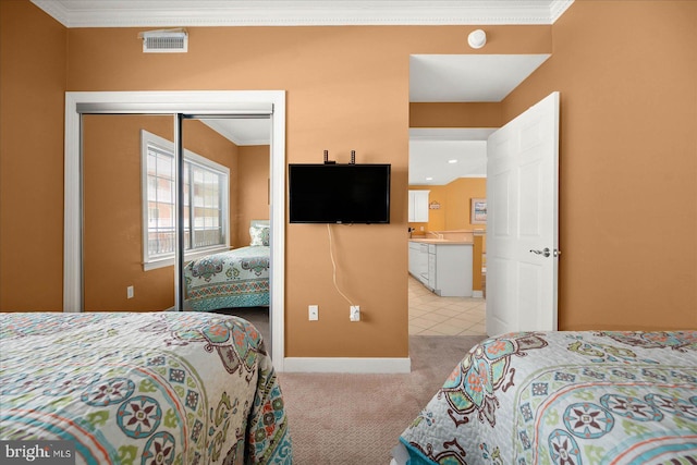 bedroom featuring ornamental molding, light colored carpet, and a closet