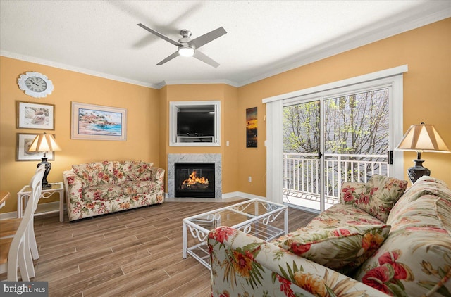 living room featuring ornamental molding, a high end fireplace, ceiling fan, and hardwood / wood-style floors