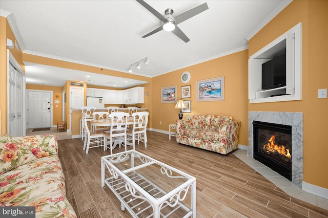 living room featuring rail lighting, crown molding, and a premium fireplace