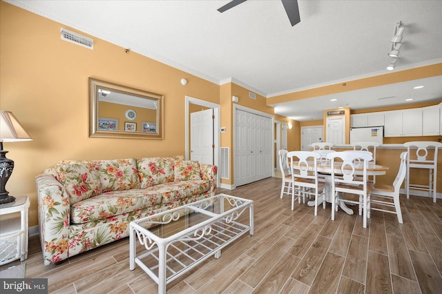 living room with light hardwood / wood-style flooring, ceiling fan, rail lighting, and a textured ceiling