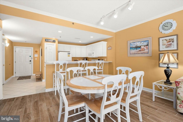 dining room with crown molding, light tile floors, and track lighting