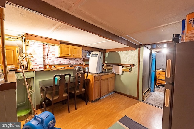 kitchen featuring backsplash, light wood-type flooring, and fridge